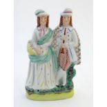 A Staffordshire pottery figural group depicting two figures, one with a basket of flowers, the other