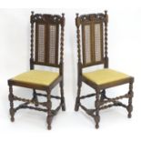 A pair of early / mid 20thC oak chairs with carved pierced top rails, caned backrests flanked by
