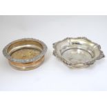 Two silver plate wine bottle coasters, one with turned wooden base. the largest 8" wide (2) Please