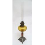 A late 19thC oil lamp, the silver plated base supporting a granite column below a peach glass