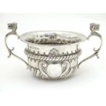 A silver sugar bowl with embossed decoration and twin handles, the handles with animal head