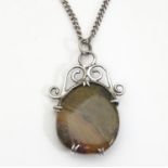 A white metal pendant set with polished hardstone cabochon. Together with a silver chain. The