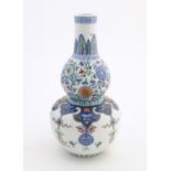 A Chinese double gourd vase with doucai style decoration with scrolling floral and foliate detail.