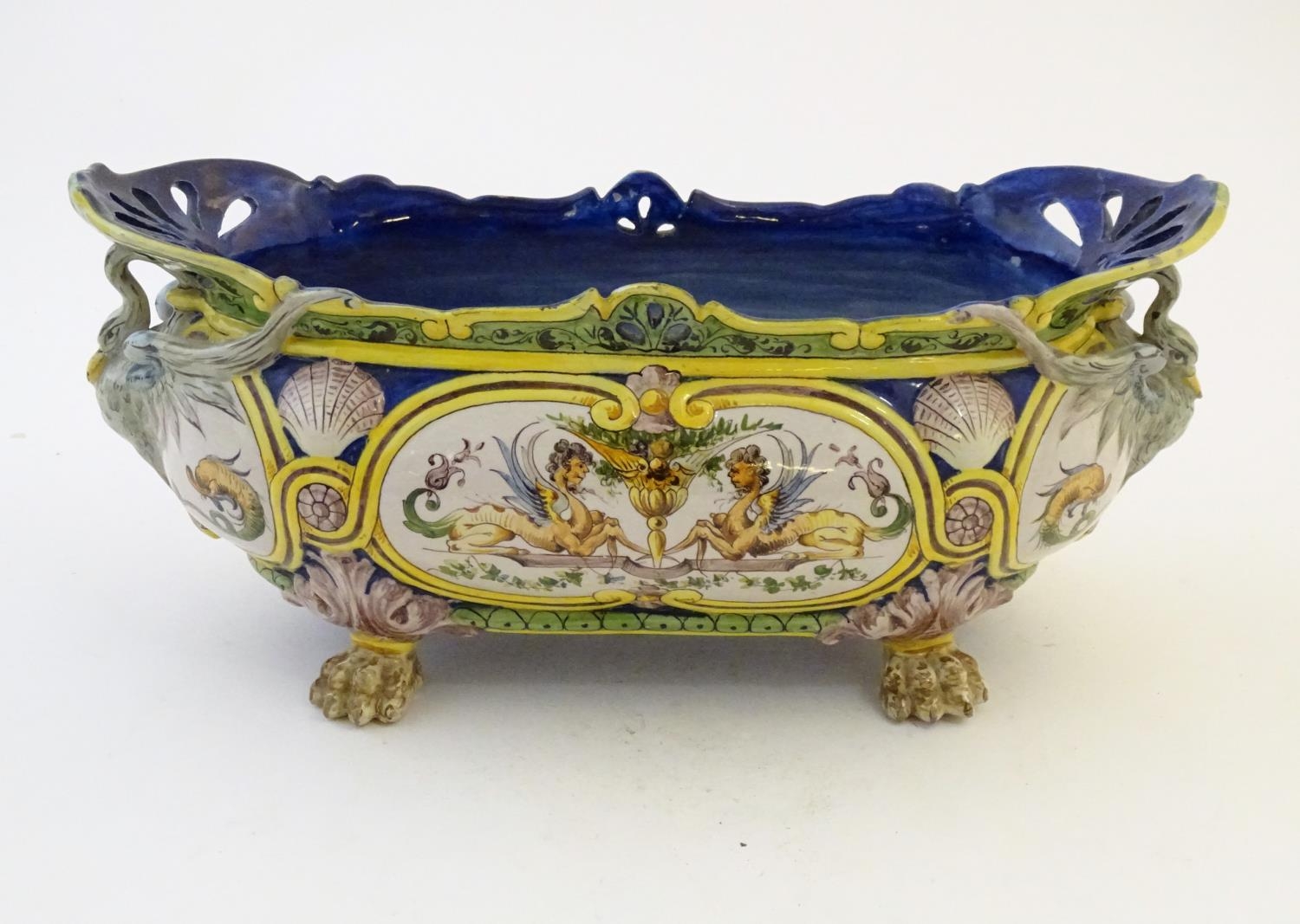 An Italian faience planter of oblong form on claw feet with panelled grotesque decoration