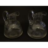 A pair of late 19thC glass jugs, decorated with etched necks and bladed flute cuts, each 5 1/2" tall