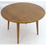 Vintage retro, Mid-century: A circular teak dining table raised on tapered legs. Labelled with '