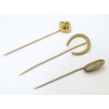 Three assorted gilt metal stick pins, one surmounted by a horse shoe, one with a pink / green