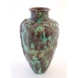 An Oriental baluster vase with a mottled green and brown glaze with relief decoration depicting