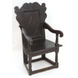 A 17thC oak Wainscot chair with a carved top rail and later carved backrest flanked by scrolled arms