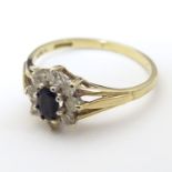 A 9ct gold ring set with central blue stone bordered by white stones, in a cluster setting. Ring