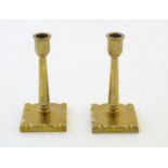 A pair of late 19th / early 20thC brass candlesticks / taper sticks, the squared bases with shaped