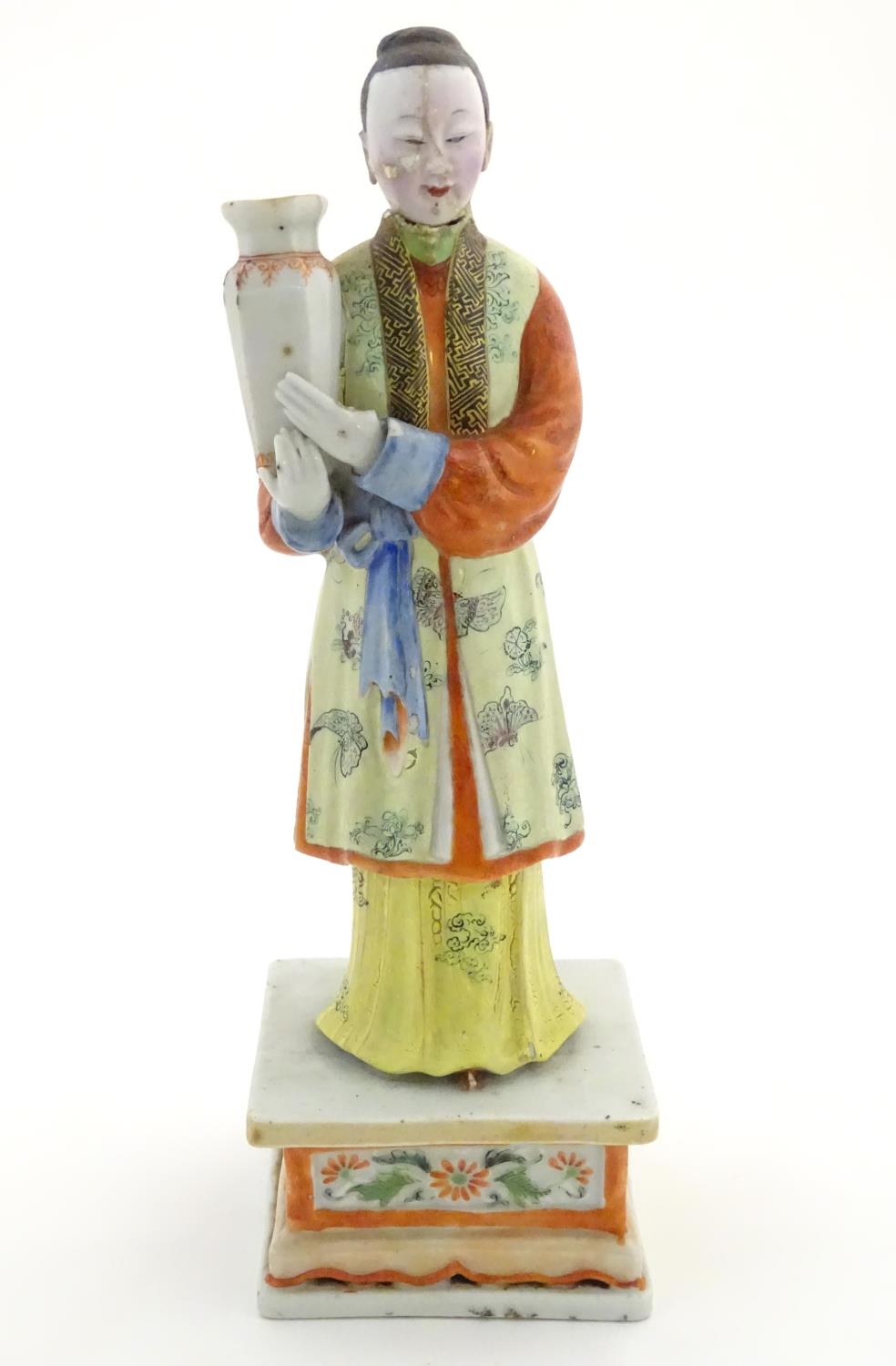 An Oriental porcelain model of a male figure wearing a kimono with butterfly and floral detail