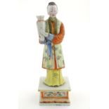 An Oriental porcelain model of a male figure wearing a kimono with butterfly and floral detail