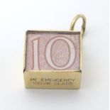 A 9ct gold novelty pendant / charm formed as a 10 shilling note folded within a 9ct gold mount