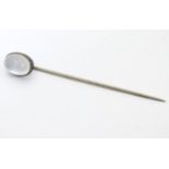 A white metal stick pin surmounted by a moonstone cabochon The whole 2 1/4" long Please Note - we do