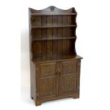 A mid 20thC oak cottage dresser by Jack Grimble, having two shelves above two carved doors and a