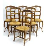 A set of early / mid 20thC oak dining chairs with shaped carved frames and having envelope rush