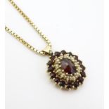 A 9ct gold pendant set with garnets and seed pearls, on a 9ct gold chain. Approx. 16" long Please
