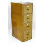 A mid 20thC panelled light oak filing cabinet, with four drawers, brass handles and label frames,