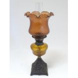 A late 19thC Duplex oil lamp, with bronzed glass shade and reservoir, standing on a cast iron base