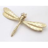 A vintage gilt metal brooch / pin formed as a dragon fly with white stone detail to eyes. 2" wide