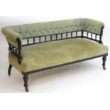 A late 19thC Aesthetic movement ebonised three seater sofa with a deep buttoned back rest and ring