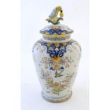 A Continental faience vase and cover with floral and foliate decoration. The cover with a finial