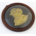 A 20thC gilt metal wall plaque depicting Charles Dickens within a circular frame with convex