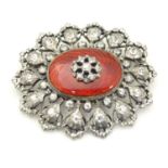 A silver brooch set with white stones and red guilloche enamel detail. Hallmarked London 1955