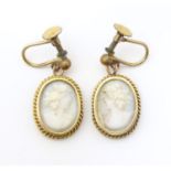 A pair of gilt metal drop earrings set with white carved cameo detail. Approx. 3/4" long Please Note