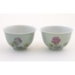 A pair of Chinese tea bowls decorated with flowers and Oriental script. Character marks under.