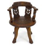 A late 19thC oak captains chair with a carved backrest, arms and two pierced back splats above a