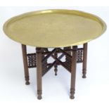 A late 19thC / early 20thC Islamic tray on stand, having a brass incised tray above a folding