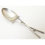 A silver teaspoon, the handle formed as crossed golf clubs with golf ball detail, hallmarked