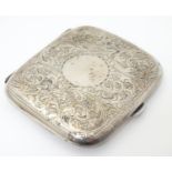 A silver cigarette case with engraved acanthus scroll decoration and gilded interior. Hallmarked