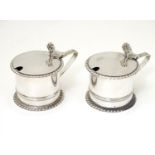 A pair of silver mustard pots with blue glass liners, hallmarked London 1909, maker Wakely &