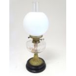 An early 20thC oil table lamp, the white globular glass shade supported by a clear cut glass