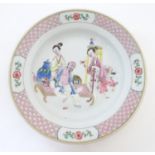 A Chinese famille rose plate decorated with an interior scene with an elderly scholar on a day bed