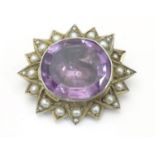 An late 19th / early 20thC white metal brooch set with central amethyst bordered by pearls.