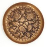 An Arts & Crafts style copper dish of circular form with embossed crane / stork bird and flower
