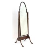 An early 20thC walnut cheval mirror in the Queen Anne style with an ogee shape and standing on