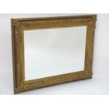 A late 19thC / early 20thC gilt wood and gesso framed mirror with a bevelled glass centre. 38"
