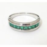 A silver ring set with 10 channel set emeralds. Ring size approx N 1/2 Please Note - we do not