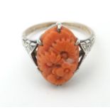 A 9ct gold and silver ring set with coral cabochon with engraved floral decoration. Ring size approx
