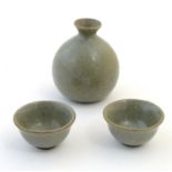 A studio pottery Japanese saki set with a crackle glaze, comprising a saki bottle with pinch