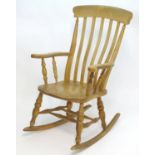 An early 20thC lathe back rocking chair with swept arms, turned tapering supports and a shaped