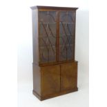 An early 20thC mahogany cupboard bookcase, having a moulded cornice with Greek key decoration