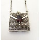 A silver pendant / vinaigrette formed as a purse / handbag, set with marcasite and red stone detail.