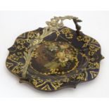 A Victorian papier mache dish with swing handle with lacquered and painted decoration depicting