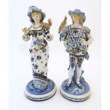 A pair of blue and white KPM figures with gilt highlights, comprising a female figure wearing a
